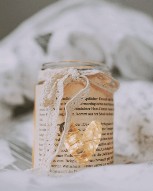 glass jar wrapped in book page with fairy lights inside